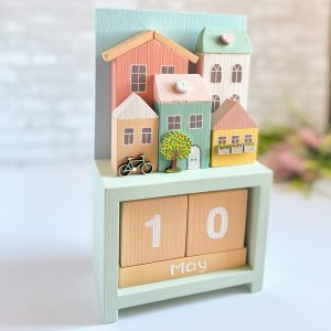 Wooden perpetual calendar with miniature houses for home decor.