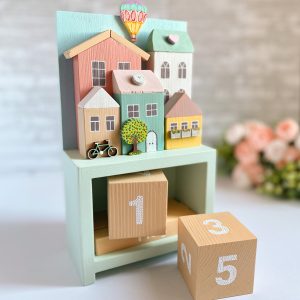Wooden perpetual calendar with miniature houses for home decor.