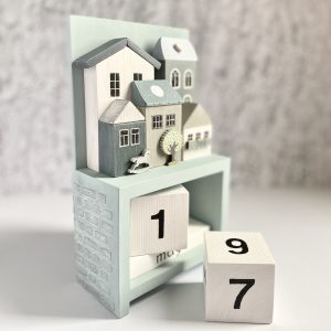 Wooden perpetual calendar with miniature houses for home decor.