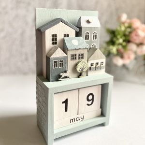 Wooden perpetual calendar with miniature houses for home decor.